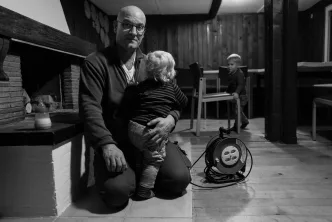 Mann mit zwei Kindern in gemütlichem Wohnzimmer.
