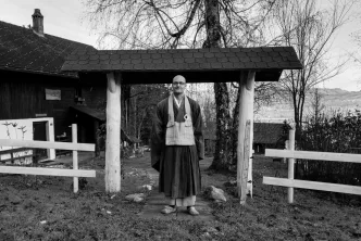 Person in traditioneller Kleidung vor Holztor